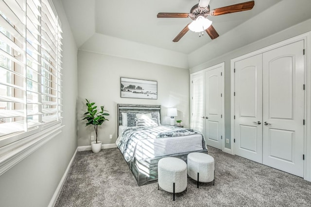 bedroom with ceiling fan, lofted ceiling, two closets, and carpet floors