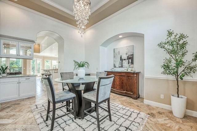 dining space with a chandelier, crown molding, and a high ceiling