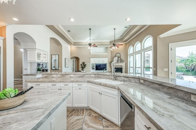 kitchen featuring ceiling fan, dishwasher, white cabinets, light stone counters, and sink