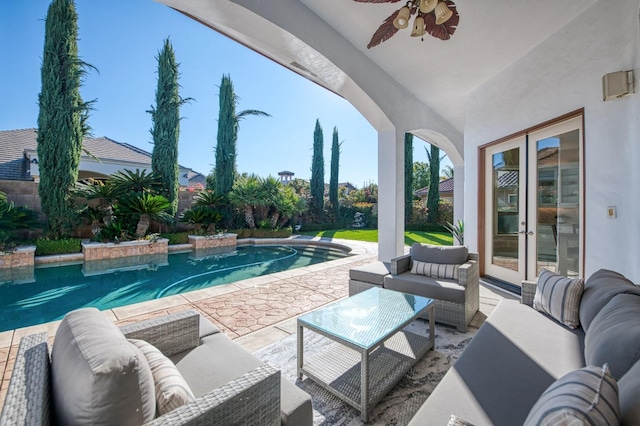 view of pool with ceiling fan, a patio area, an outdoor living space, and french doors