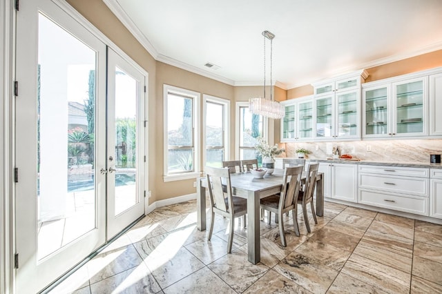 dining area featuring crown molding, french doors, and an inviting chandelier