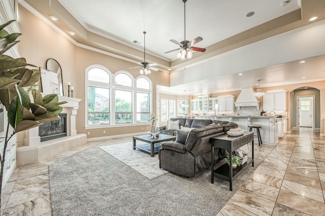 living room with ceiling fan, crown molding, a tray ceiling, and sink