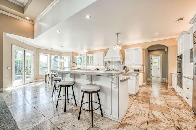 kitchen with white cabinets, a breakfast bar, pendant lighting, and a large island