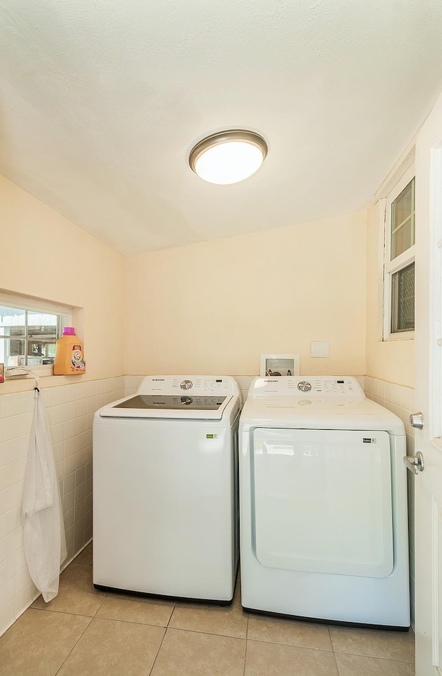 laundry room featuring light tile patterned flooring, tile walls, and independent washer and dryer