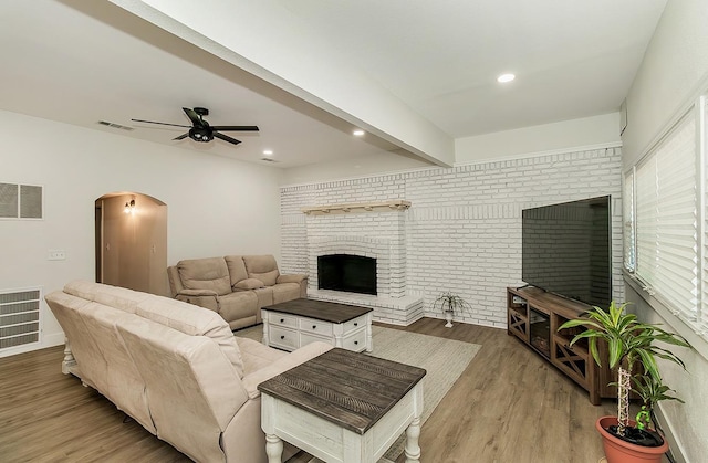 living room with beam ceiling, ceiling fan, brick wall, and hardwood / wood-style flooring