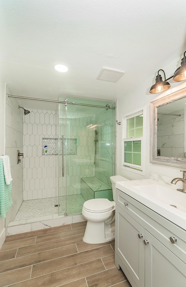 bathroom featuring an enclosed shower, vanity, and toilet