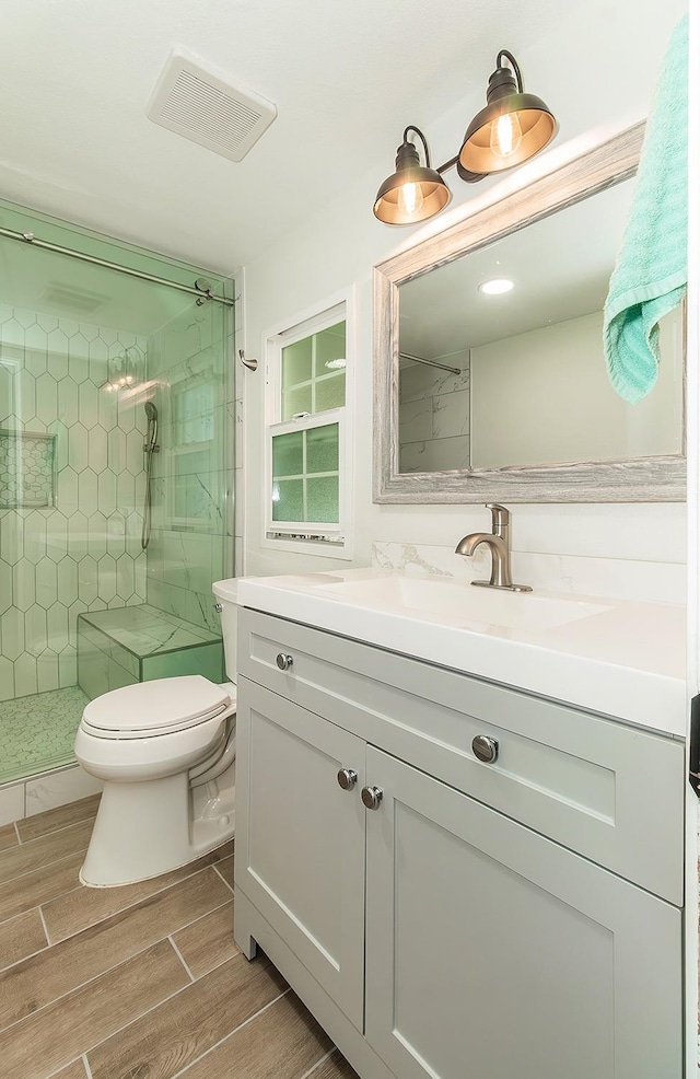 bathroom featuring toilet, a tile shower, and vanity