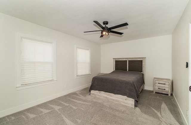 bedroom with ceiling fan, carpet floors, and a textured ceiling