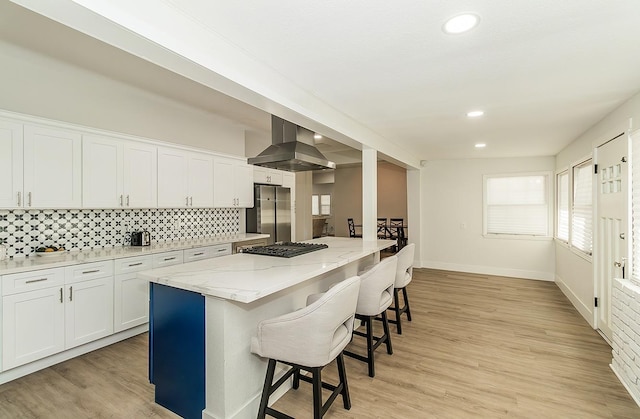 kitchen featuring appliances with stainless steel finishes, white cabinetry, island range hood, and a center island