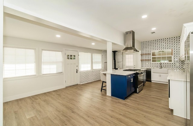 kitchen with a kitchen island, island exhaust hood, white cabinetry, stainless steel range oven, and a kitchen breakfast bar