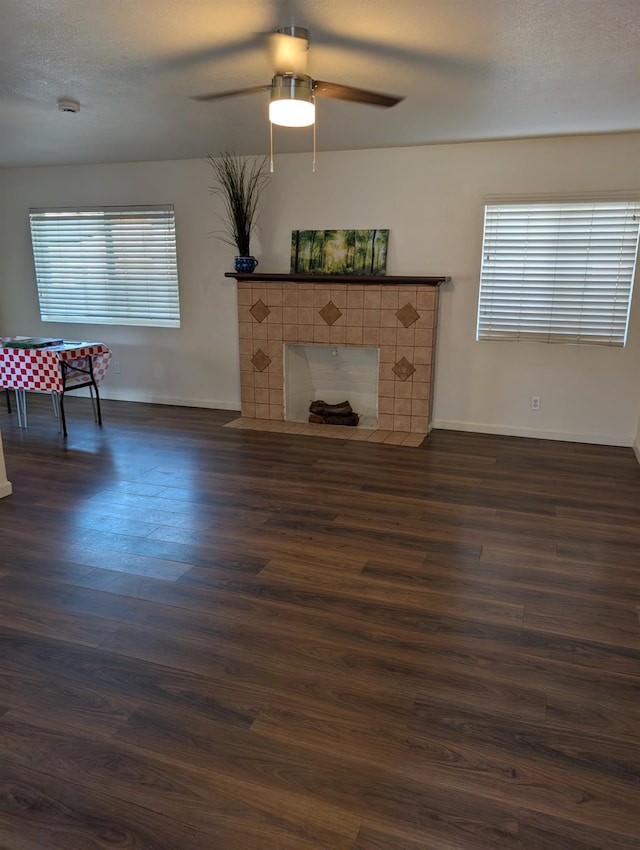 living room with ceiling fan, dark wood-type flooring, and a tiled fireplace