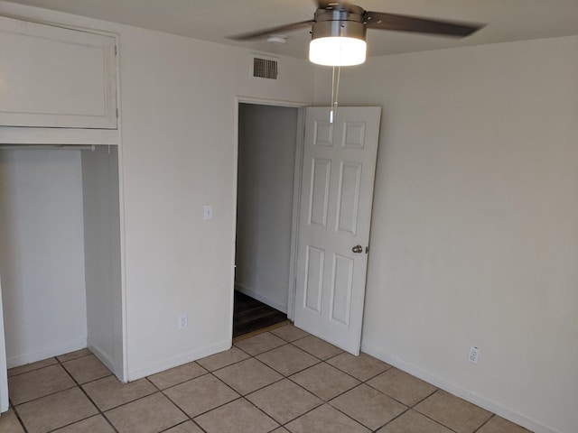 unfurnished bedroom with a closet, light tile patterned floors, and ceiling fan