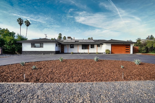 ranch-style home featuring a garage and solar panels