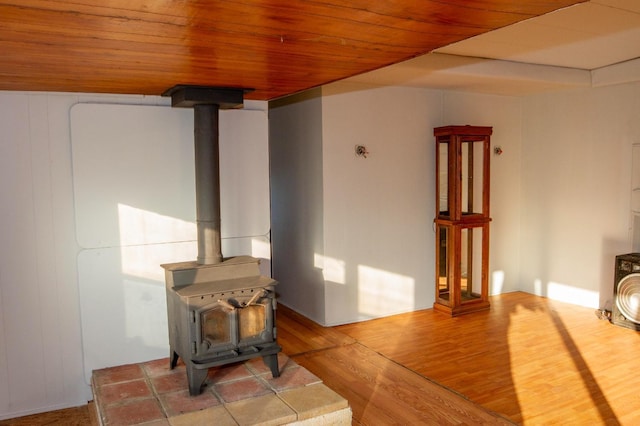 living room featuring wood ceiling, a wood stove, and hardwood / wood-style floors