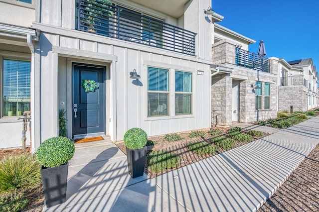 view of exterior entry featuring stone siding and board and batten siding