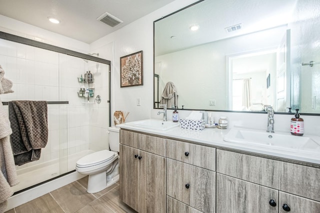 bathroom featuring toilet, a shower stall, visible vents, and a sink