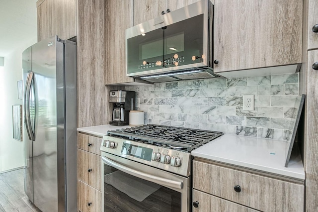 kitchen featuring stainless steel appliances, light countertops, light brown cabinets, and decorative backsplash