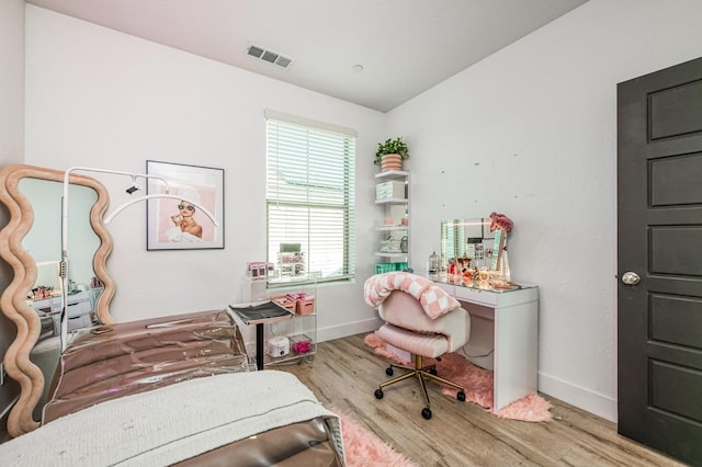 bedroom featuring baseboards, visible vents, vaulted ceiling, and wood finished floors