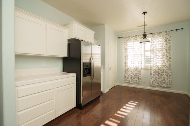 kitchen with stainless steel fridge with ice dispenser, tile countertops, white cabinetry, and pendant lighting