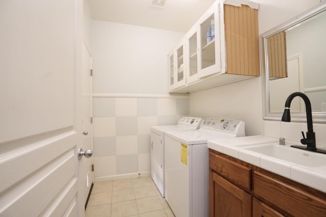 clothes washing area with cabinets, sink, light tile patterned floors, and washing machine and clothes dryer