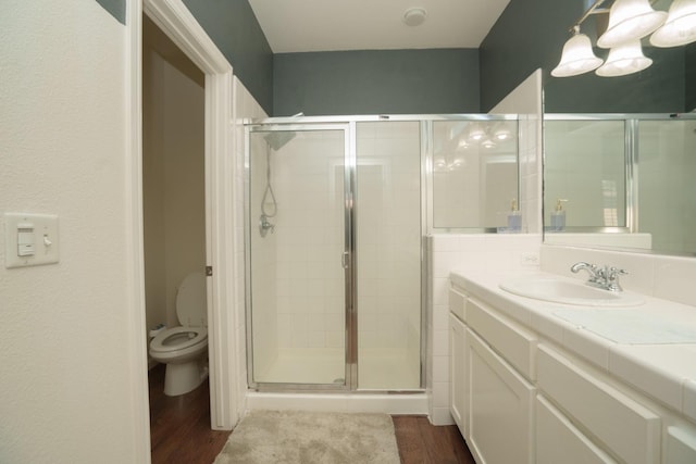 bathroom with toilet, vanity, a shower with door, and hardwood / wood-style floors