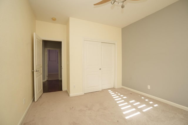 unfurnished bedroom featuring ceiling fan, light colored carpet, and a closet