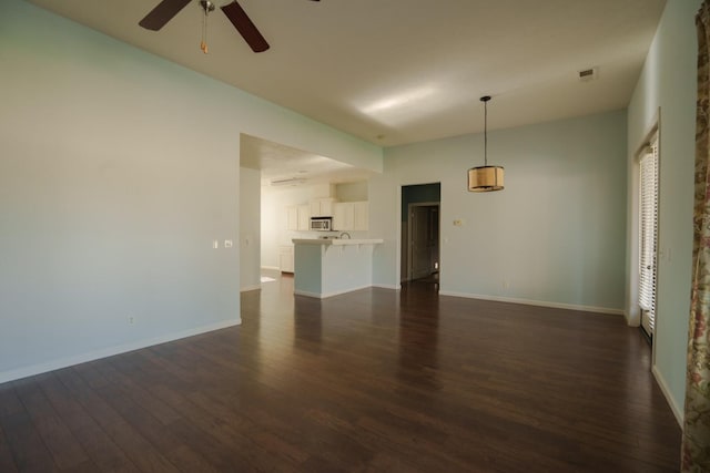 unfurnished living room featuring ceiling fan and dark hardwood / wood-style floors