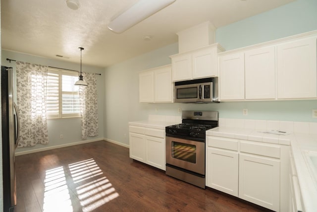 kitchen with appliances with stainless steel finishes, tile countertops, and white cabinets