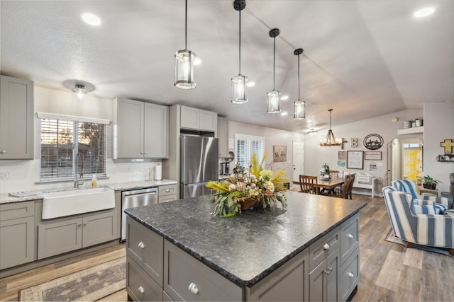 kitchen with gray cabinets, a kitchen island, sink, decorative backsplash, and stainless steel appliances
