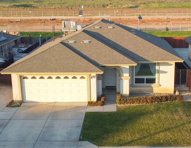 view of front facade featuring a garage, a front yard, and a rural view