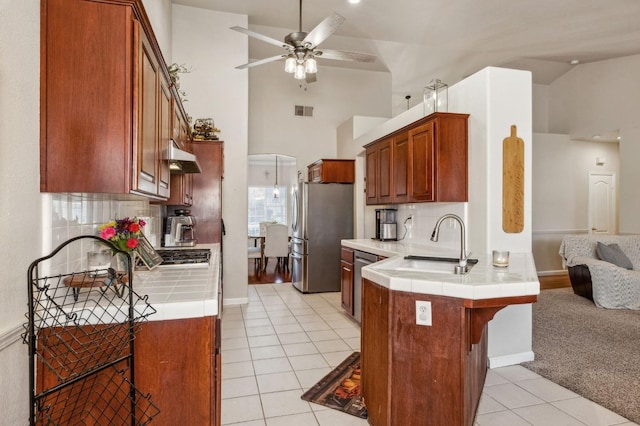 kitchen with kitchen peninsula, backsplash, appliances with stainless steel finishes, and tile countertops