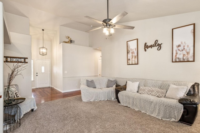 living room featuring vaulted ceiling, carpet, and ceiling fan with notable chandelier