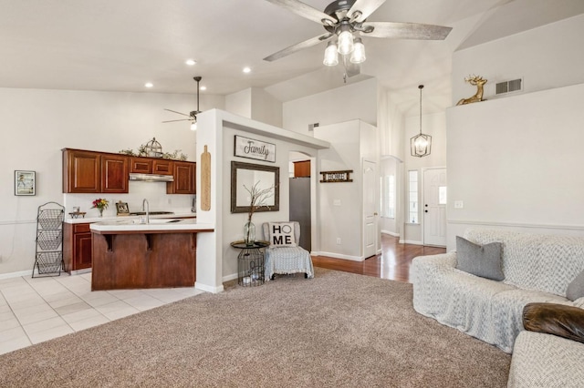 carpeted living room featuring ceiling fan, sink, and high vaulted ceiling