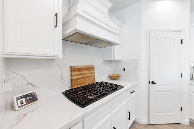 kitchen with white cabinets, tasteful backsplash, black gas stovetop, and custom exhaust hood