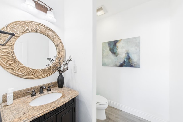 bathroom with toilet, vanity, and hardwood / wood-style flooring