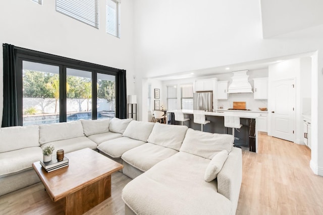 living room with light wood-type flooring and a towering ceiling