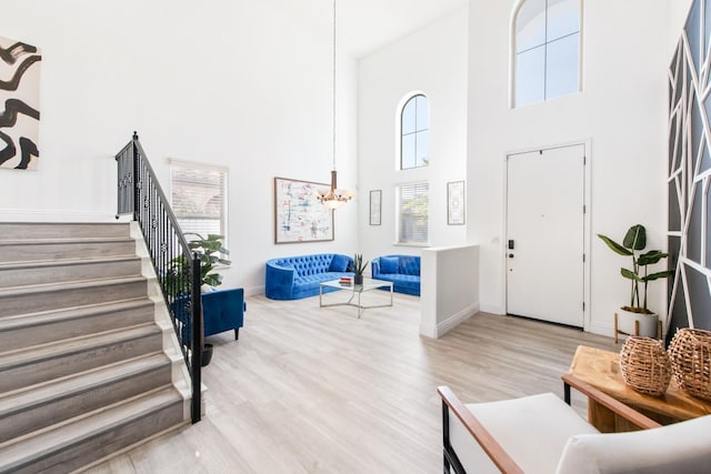 entryway with hardwood / wood-style floors, a towering ceiling, and a notable chandelier