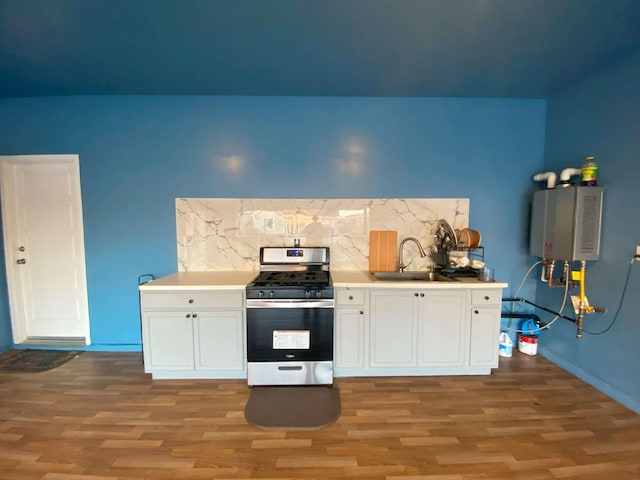 kitchen featuring tankless water heater, dark wood-type flooring, white cabinetry, stainless steel gas stove, and sink