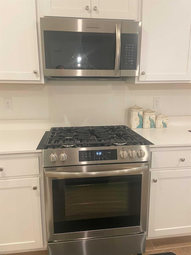 kitchen featuring hardwood / wood-style flooring, stainless steel appliances, and white cabinets