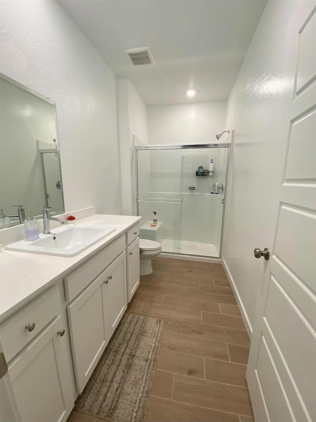 bathroom featuring toilet, walk in shower, and vanity