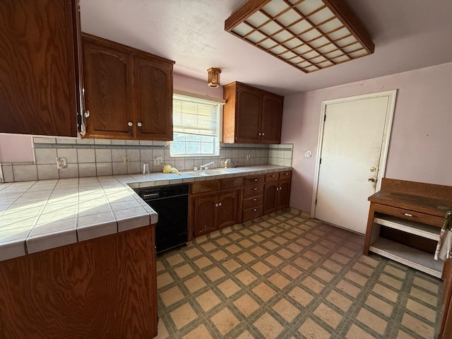 kitchen featuring tile countertops, black dishwasher, tasteful backsplash, dark brown cabinets, and sink