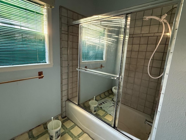 bathroom featuring toilet and bath / shower combo with glass door