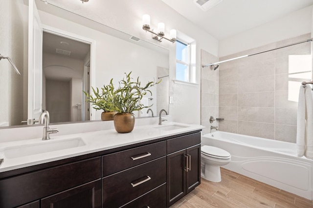 full bathroom with toilet, tiled shower / bath combo, and vanity