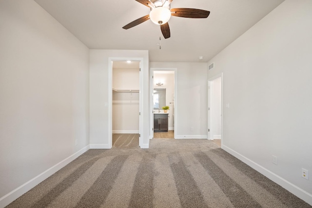 unfurnished bedroom featuring ceiling fan, light carpet, a spacious closet, and a closet