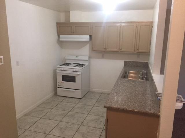 kitchen featuring light tile patterned floors, white gas range, and sink