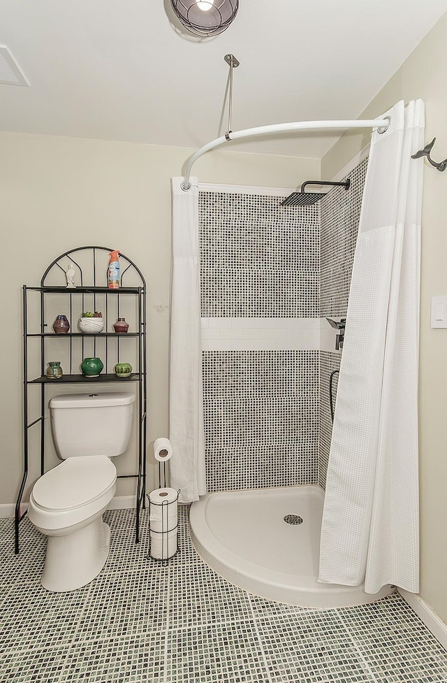 full bath featuring toilet, a shower stall, visible vents, and baseboards