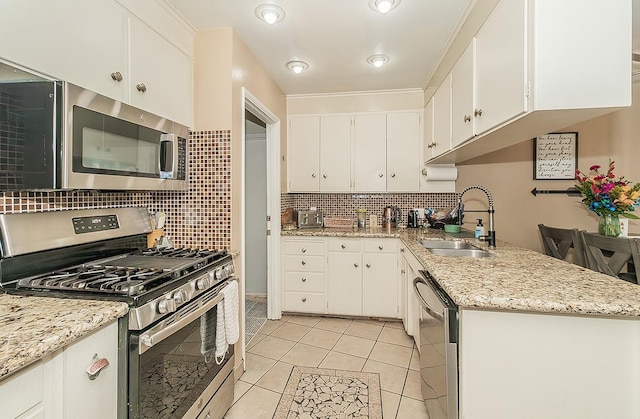 kitchen featuring appliances with stainless steel finishes, white cabinets, a sink, and decorative backsplash