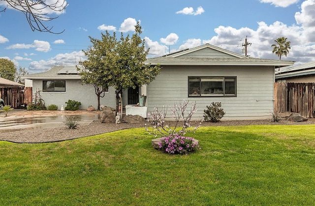 ranch-style home with fence, a front lawn, and solar panels