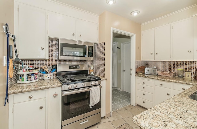 kitchen featuring light stone counters, stainless steel appliances, white cabinetry, backsplash, and light tile patterned flooring