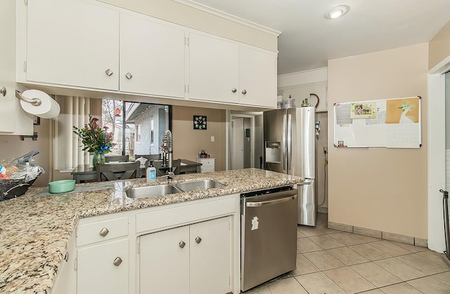 kitchen featuring light tile patterned floors, stainless steel appliances, white cabinets, a sink, and light stone countertops